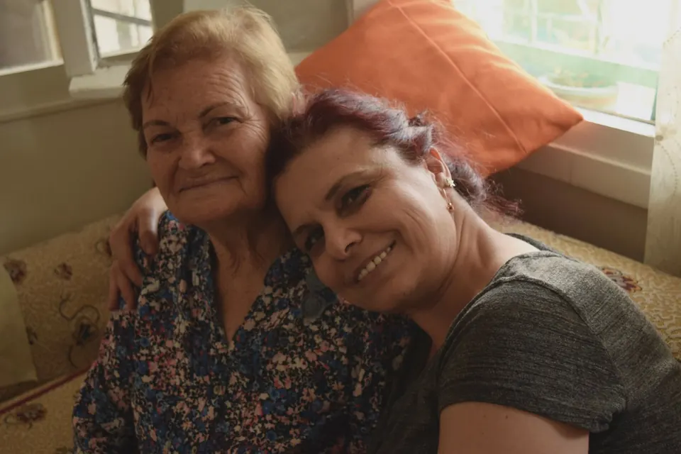 Une femme âgée et une femme plus jeune, joue contre joue, sourient